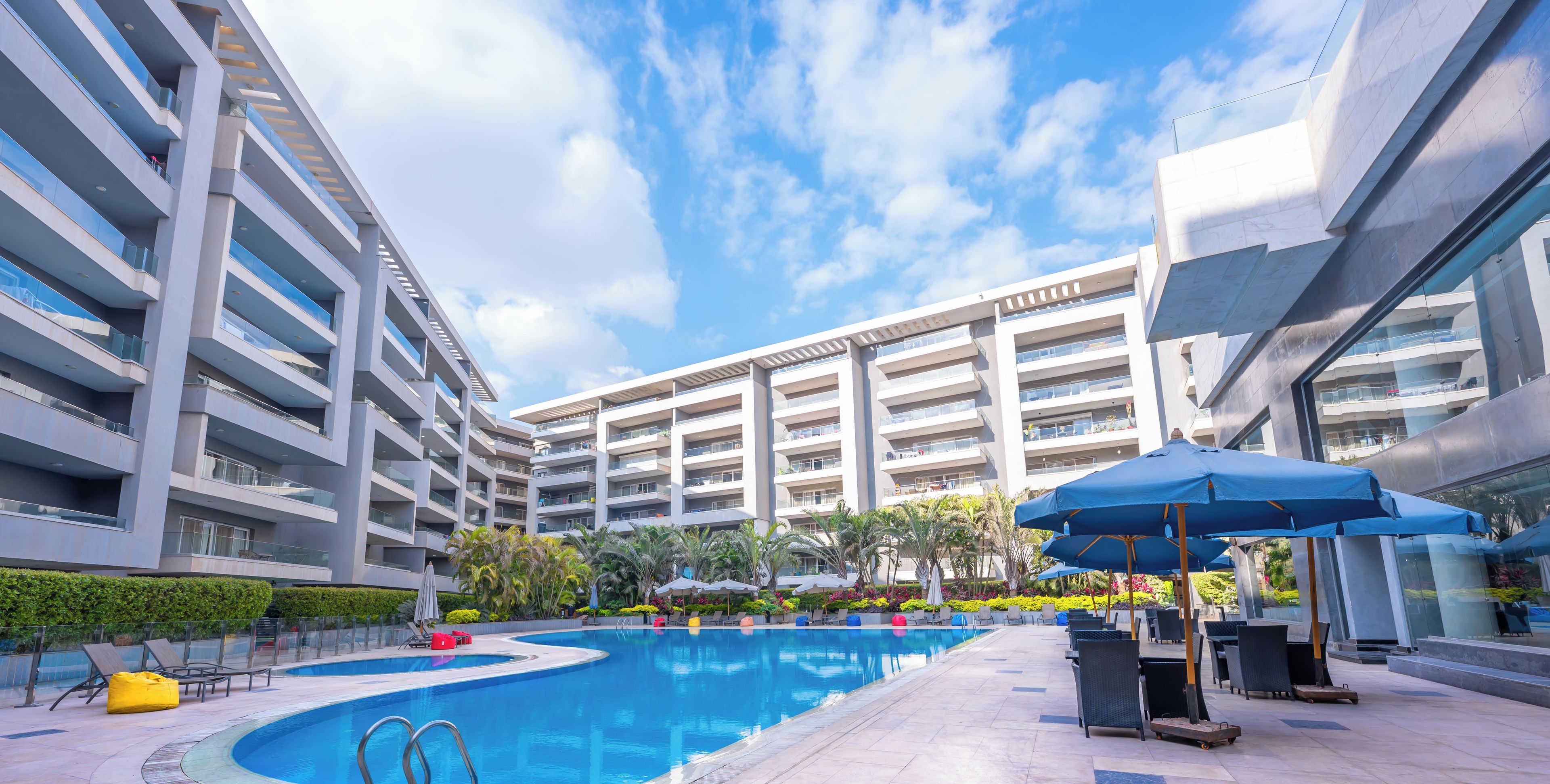 Un hotel moderno con piscina central, zona de estar al aire libre y vistas despejadas de los edificios circundantes.