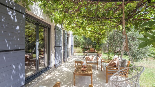 A covered patio area with outdoor furniture, a swing, and a view of the surrounding garden. - Peaceful farmhouse surrounded by olive trees.  Only 15 minutes from beaches and mountains (Opio)