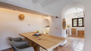 A kitchen with a wooden island, two grey chairs, a bowl of fruit, and a hanging light fixture. - My Rental Homes - Can Cabana with private pool, air conditioning and wifi (Pollença)
