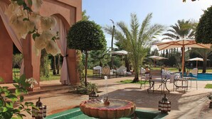 A courtyard with a fountain, outdoor seating, and a pool. - My Rental Homes - Dar Maril with pool, tennis court and garden (Oulad Jellal)