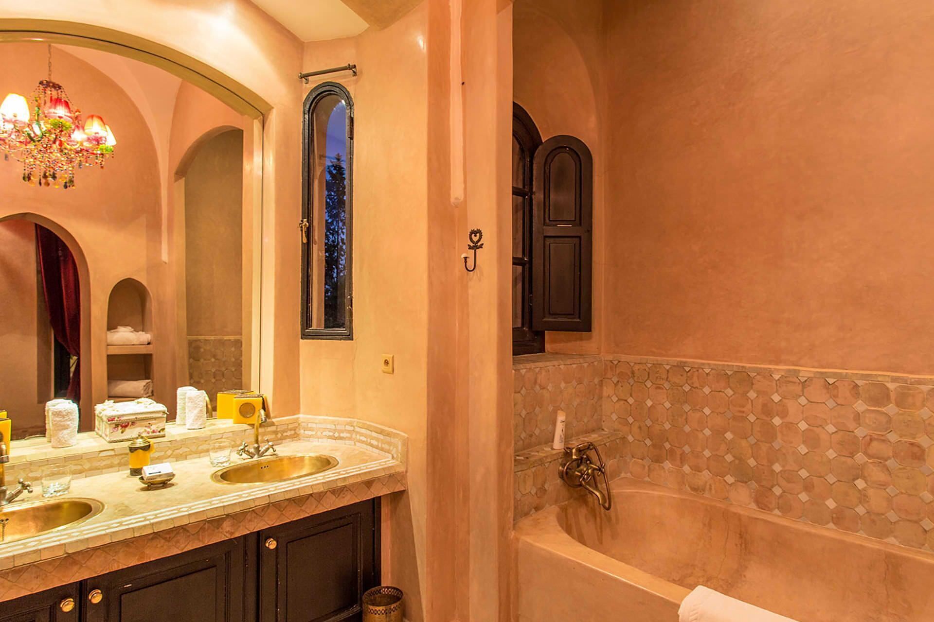 Une salle de bain dotée d’une grande vasque, d’une baignoire et d’un lustre.