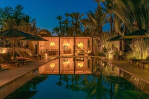 A poolside area with lounge chairs, umbrellas, and a reflection pool. - My Rental Homes - Dar Sun with pool, garden and tennis court (Marrakesh)