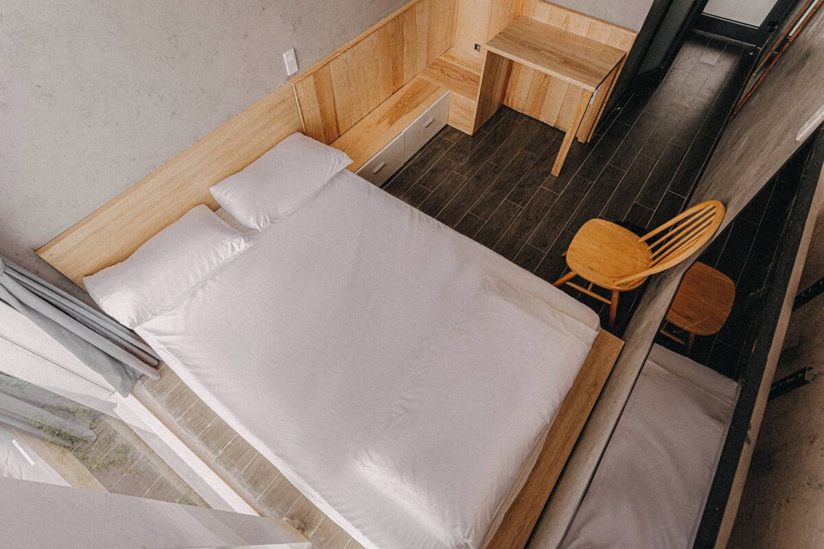 Una habitación pequeña con cama, una silla de madera y un escritorio.