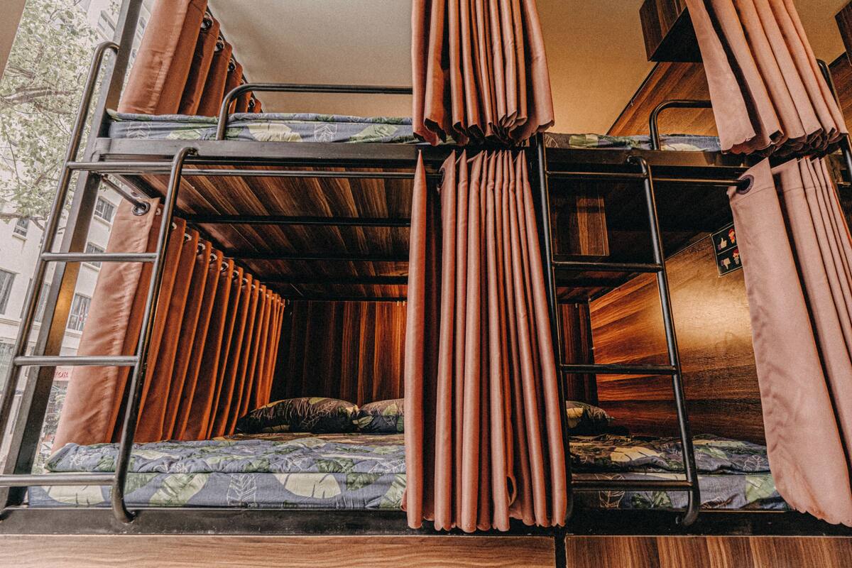 Una cama litera con cortinas, una escalera y un colchón estampado con motivos florales.