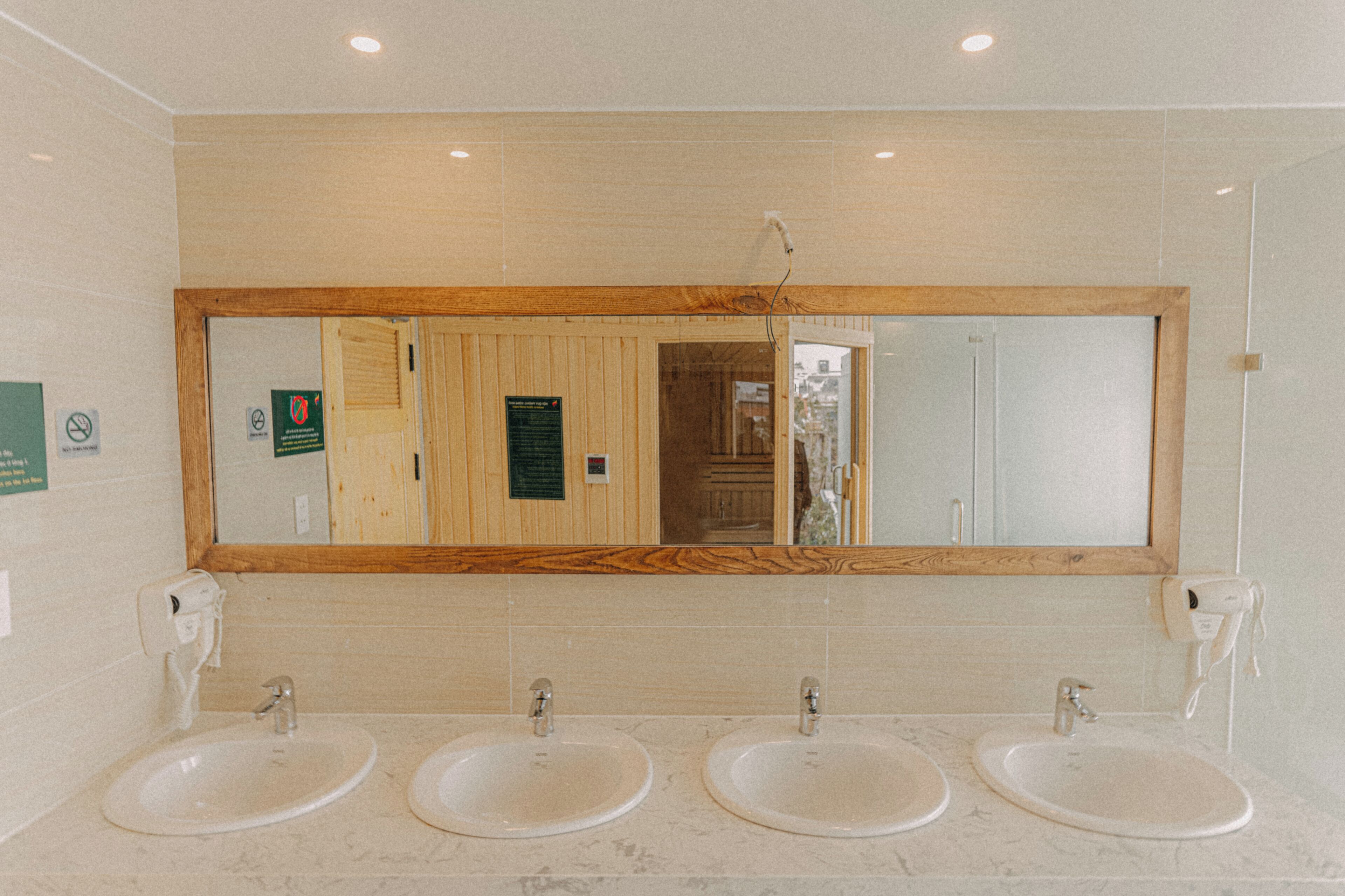 A bathroom with three sinks, a large mirror, and wooden paneling.