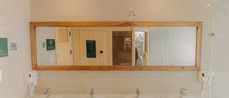 A bathroom with three sinks, a large mirror, and wooden paneling.