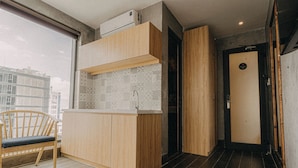 A modern kitchen with wooden cabinets, a built-in sink, and a window overlooking a cityscape. - SNite Hotel & Dorm-Danang Dragon Bridge (Da Nang)