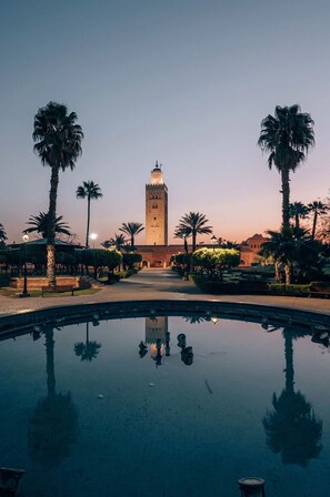 A serene pool reflecting palm trees and a towered building, likely a historic site. - My Rental Homes - Villa Amador in golf club and SPA, with private pool (Diabat)