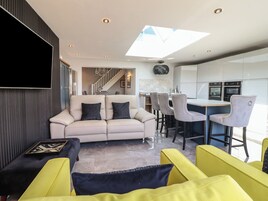Una sala moderna con un sofá, sillones amarillos y un comedor con taburetes de bar.