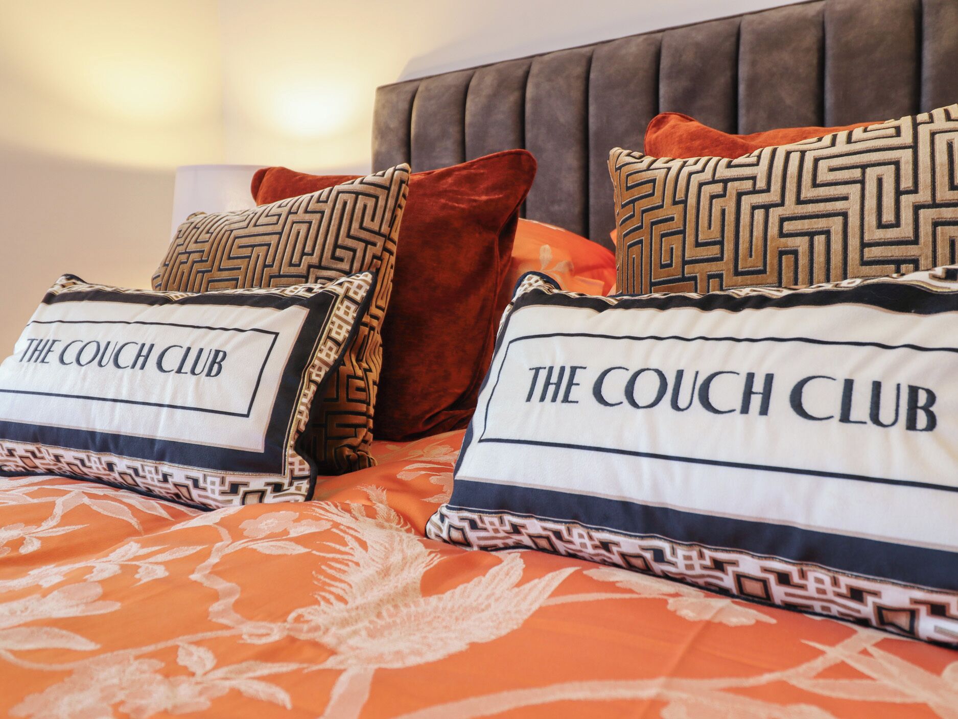 Una cama con varios cojines, algunos con texto y diseños geométricos.
