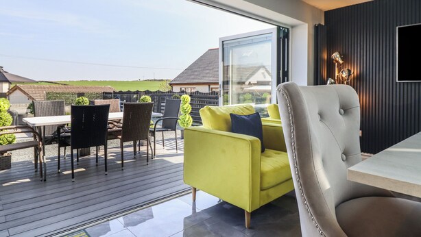 A modern living room with a large window, a yellow sofa, and a grey armchair. - Bronallt (Cemaes Bay)