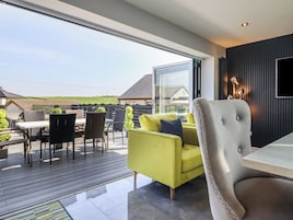 Una sala de estar moderna con un ventanal grande, un sofá amarillo y un sillón gris.