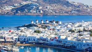 Un pueblo costero con edificios blancos, molinos de viento y barcos.
