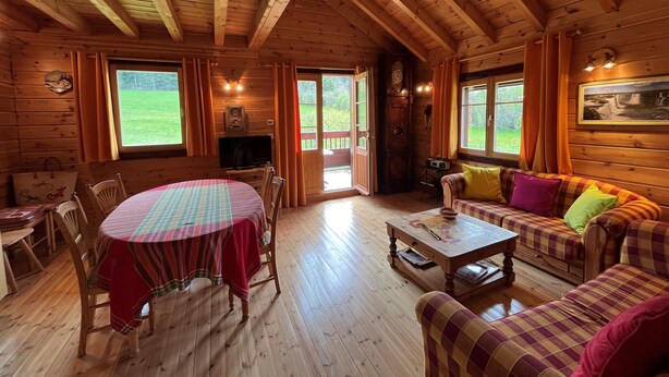 Een houten cabinemeubilair met een eettafel, stoelen, een bank en een televisie.