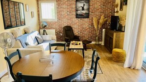 A cozy living room with a brick wall, a round wooden dining table, and comfortable seating.