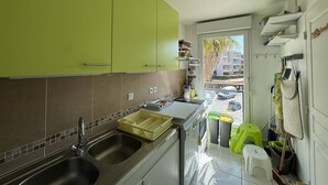 A kitchen with green cabinets, a double sink, and a view of the street outside.