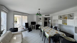 A spacious living area with a dining table, sofa, and TV.