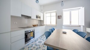 Een moderne keuken met witte kasten, een houten tafel en blauwe stoelen.