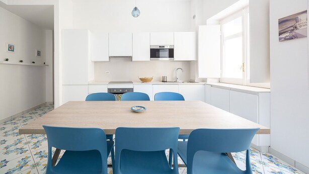 Een moderne keuken met witte kasten, een oven van roestvrij staal en een raam dat natuurlijk licht binnenlaat.