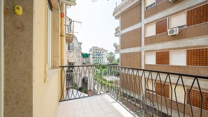Een smal balkon met betegelde vloer en een metalen hekwerk.
