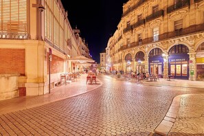 A cobblestone street lined with cafes and restaurants, featuring outdoor seating and ornate architecture. - Le Paul Riquet by Béziers 1609 Résidences (Béziers)