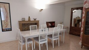 A dining area with a white table and chairs, a brick fireplace, and a large mirror. - Gîte "Chez Tété (Meursault)