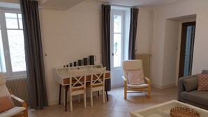 A living room with a white table, two chairs, a sofa, and a chair with a cushion. - Gîte "Chez Tété (Meursault)