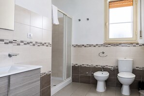 Een badkamer met douche, toilet, hygiëneschuimer en wastafel.