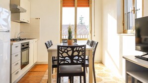 Une cuisine compacte avec un coin repas, un téléviseur et une fenêtre donnant sur un immeuble.