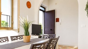Un espace repas comprenant une table, des chaises, une plante en pot, un téléviseur et une porte.