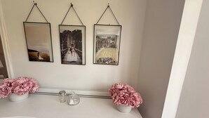 Une commode blanche, et au-dessus, sur le mur, trois photographies encadrées.