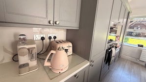 Une cuisine avec des meubles de couleur grise, un grille-pain, une bouilloire et une machine à café posés sur le plan de travail.