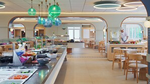 A buffet area with a variety of food items, a chef preparing food, and a seating area with tables and chairs. - Ponient Aparthotel Marinada by PortAventura World (Salou)