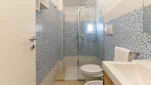 Een badkamer met een glazen douchecabine, een wit toilet en een bad met een witte handdoek.