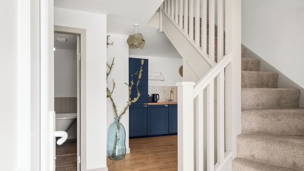 A staircase leading to a landing with a kitchen area in the background. - Luxury 2 Bedroom Cottage, with private courtyard and garden. (Killin)