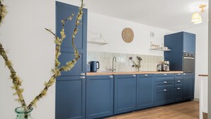 A modern kitchen with blue cabinets, a wooden countertop, a clock, and a stove. - Luxury 2 Bedroom Cottage, with private courtyard and garden. (Killin)