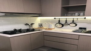 Eine moderne Küche mit Gasherd, weißer Arbeitsplatte, Holzschränken und einer Rückwand.
