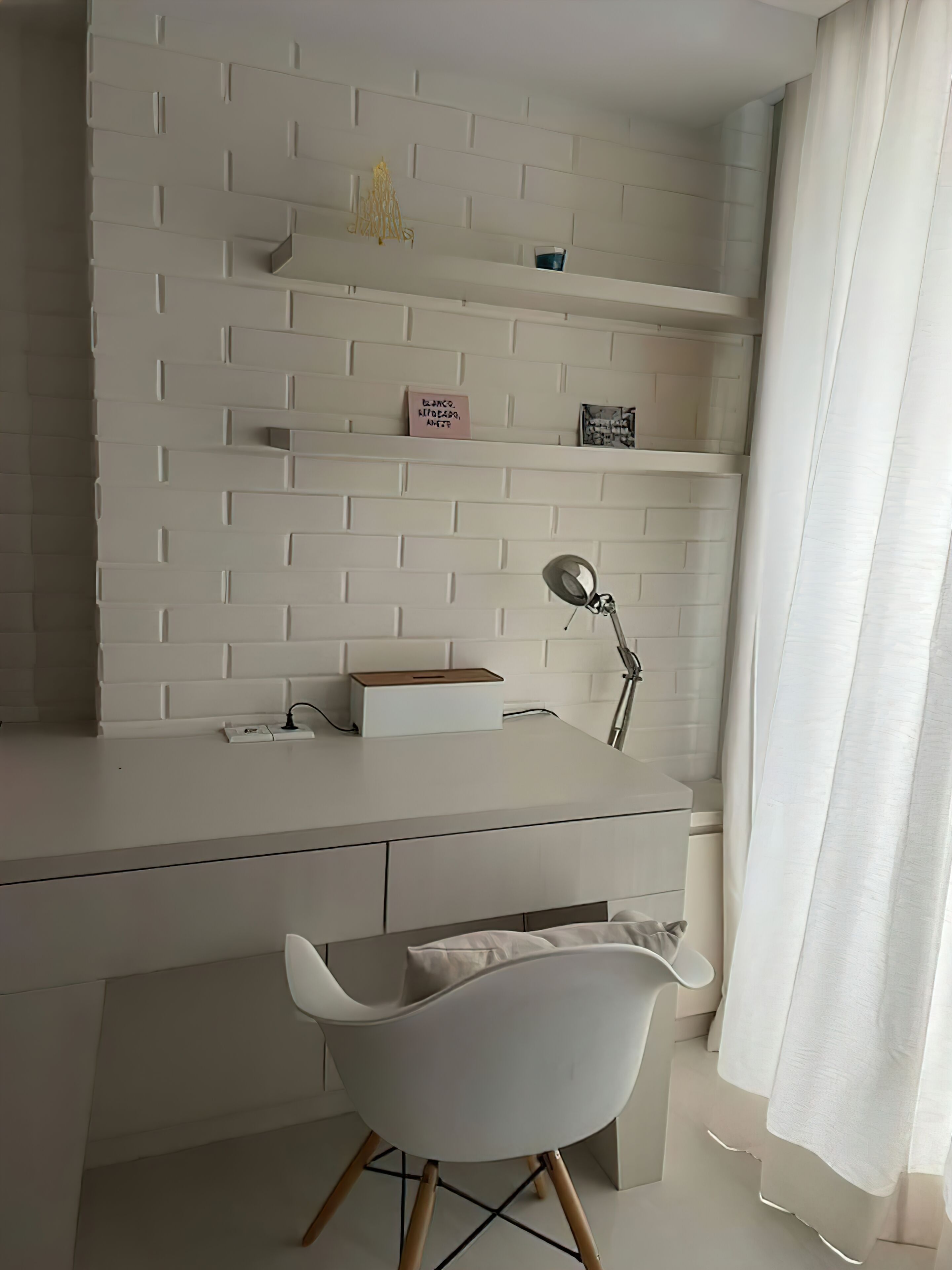 Una habitación moderna y minimalista con un escritorio blanco, una silla y estanterías con objetos decorativos.