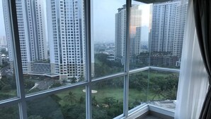 Eine hohe Wohnung mit großen Fenstern und Blick auf umliegende Gebäude und Grünflächen.