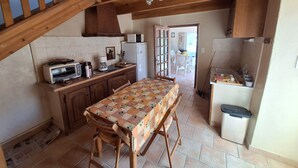 Una cocina con vigas de madera, una mesa de comedor con mantel estampado, un refrigerador y un microondas.
