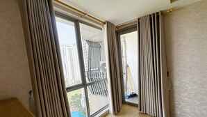 Ein Zimmer mit großen Fenstern, Holzboden und Blick auf hohe Gebäude sowie einen Pool im Freien.