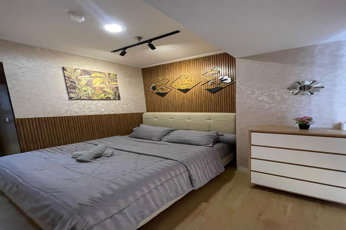 A bedroom with a bed, a dresser, and wall art.