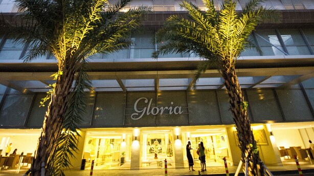 Ein Hochhaus-Hotel mit mehreren Stockwerken, einer sichtbaren Fassade mit dem Namen "Gloria" und Palmen im Vordergrund.
