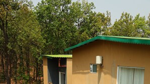 A two-story building with a swimming pool, surrounded by lush greenery and trees.