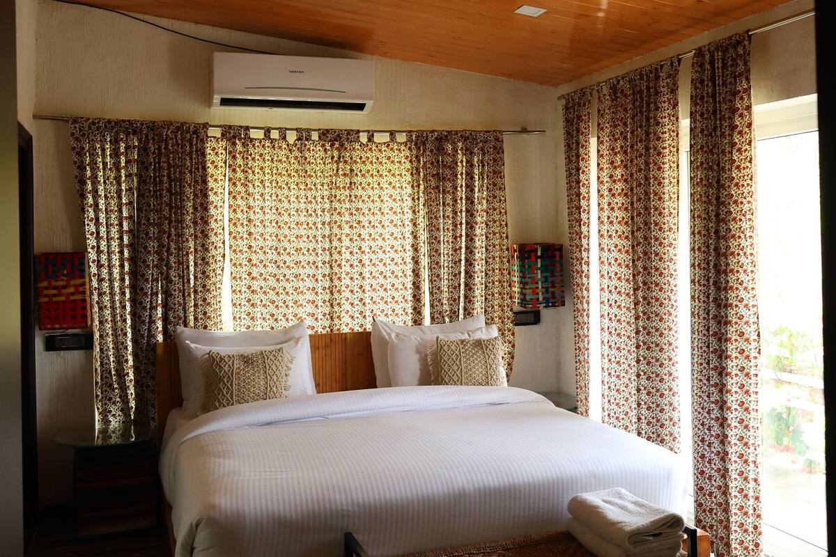 Une chambre à coucher avec un grand lit, un plafond en bois et des rideaux à motifs.