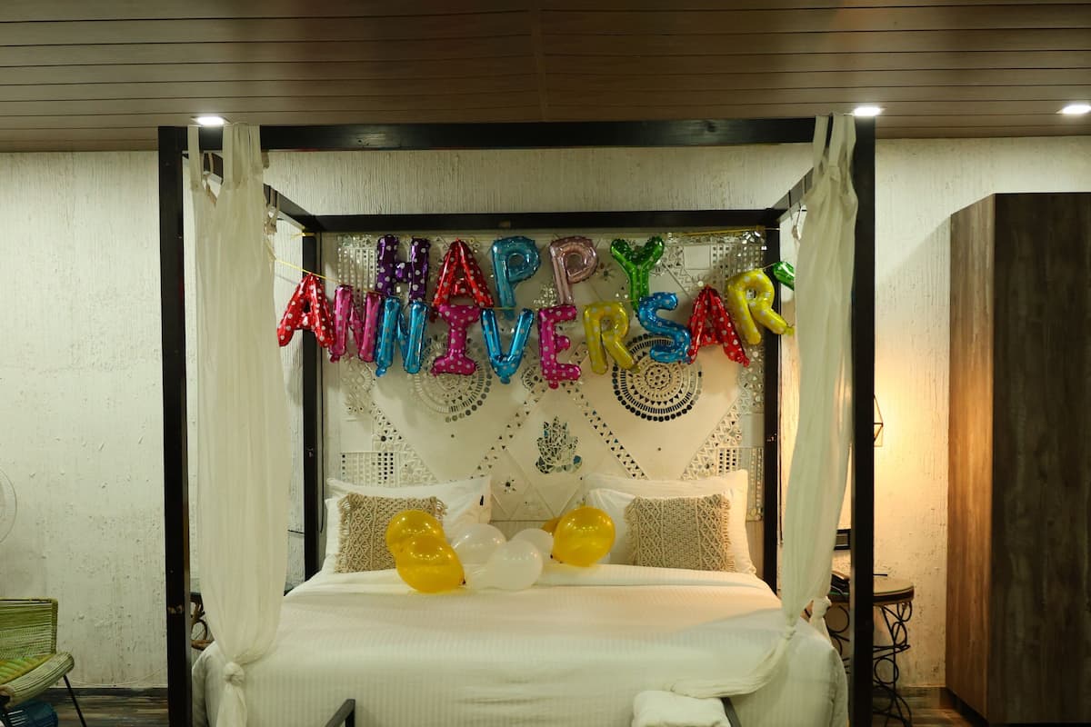 Un lit à baldaquin, décoré de ballons et d’une guirlande portant l’inscription « Joyeux anniversaire ».
