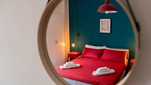 A bedroom with a red bedspread, white pillows, and a red pendant light. - B&B MilleCulure: Charming double room with private bathroom  (Napoli)