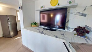 A modern kitchen with a flat-screen TV, a refrigerator, and a marble countertop. - Talia - Three Bedroom House, Sleeps 4 (Olmedo)