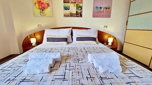 A neatly made bed with two towels, a headboard, bedside lamps, and a wall with multiple framed pictures. - Talia - Three Bedroom House, Sleeps 4 (Olmedo)