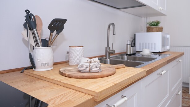 Una cocina moderna con armarios blancos, encimera de madera, un fregadero y un microondas.